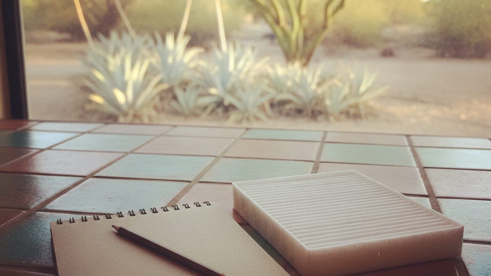 A notebook and pen on a kitchen counter in a bright Tucson home with a window showing a desert garden