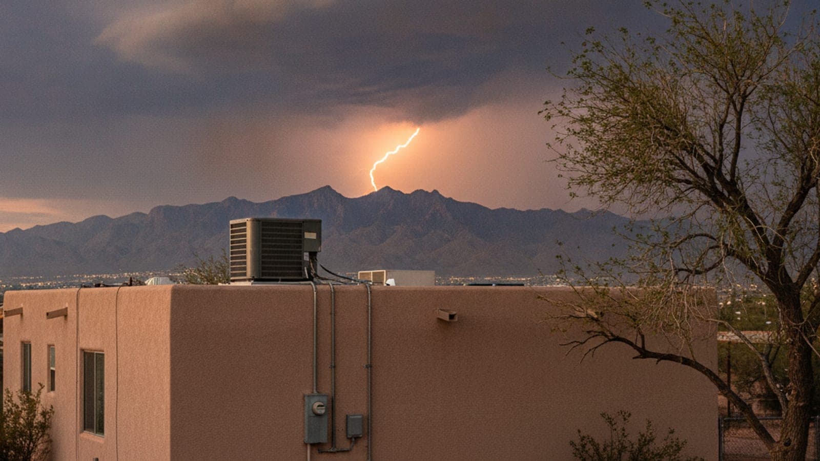 Monsoon thunderstorm clouds with distant lightning over a Tucson neighborhood and a flat-roofed stucco home with an AC condenser