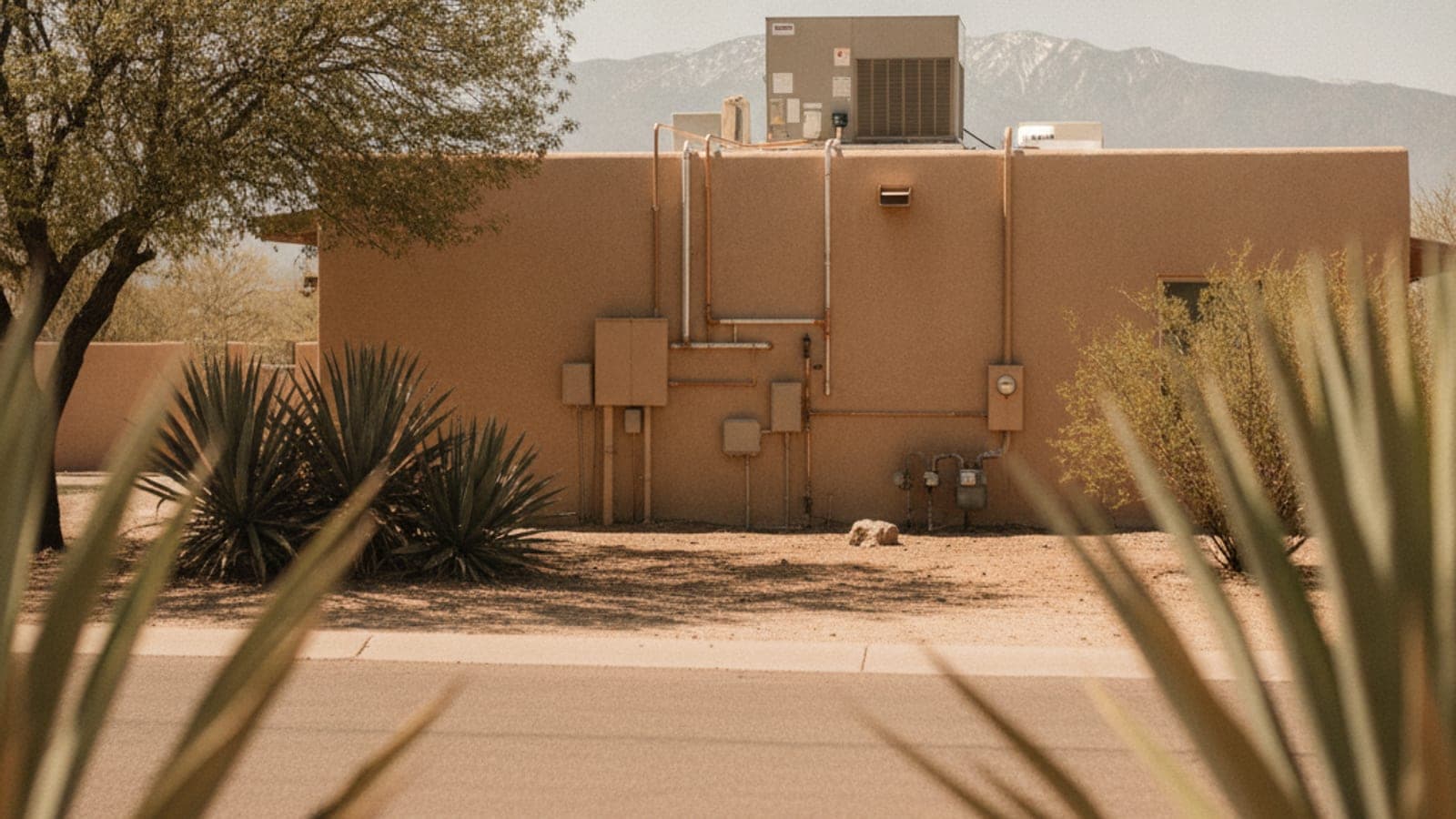 Homeowner at the front door of a Tucson stucco home looking at a thermostat on a hot day